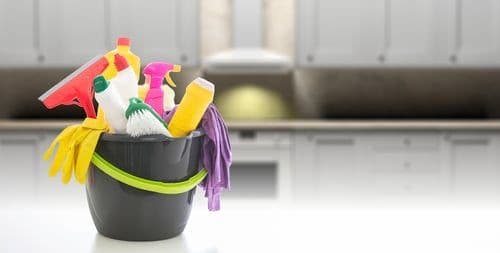 Cleaning supplies staged on a modern grey kitchen counter before a deep clean